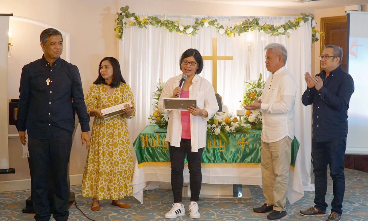 Pastor Marianne Bucud (center) and other church leaders stand in front of the altar of Sharjah United Methodist Church, located in the United Arab Emirates. Bucud became the congregation’s pastor in 2020 when the Filipino United Methodist presence in Sharjah began. Although Middle Eastern countries have varying degrees of religious tolerance, the area has been a center of growth for Filipino diaspora faith communities. Photo courtesy of Sharjah United Methodist Church Facebook page.  