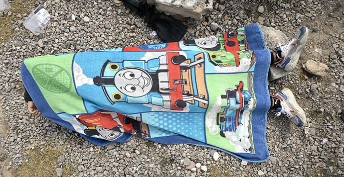 Covered by a Thomas the Tank Engine towel, a migrant sleeps along the railroad tracks in Apaxco, Mexico, where a shelter run by the Methodist Church of Mexico provides critical assistance to migrants, who often wait for days in Apaxco for a freight train to stop so they can hop aboard and continue their journey northward. Photo by the Rev. Paul Jeffrey, UM News.