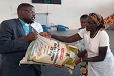 Rev. Manuel Calimbue faz a entrega simbólica de uma saco de arroz à representante dos sobreviventes das cheias. Malanje, foto de João Nhanga.