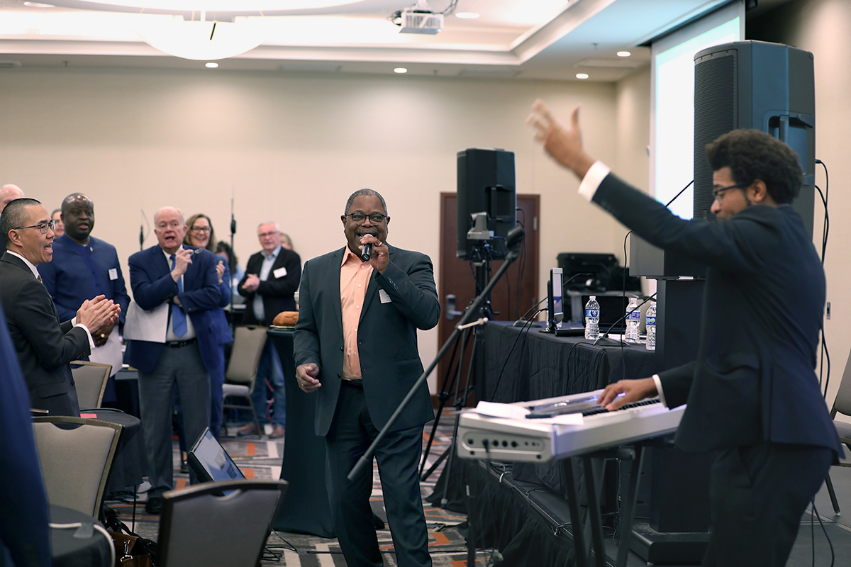 The Rev. Reggie Clemons, a General Council on Finance and Administration board member (center, with microphone), and the Rev. Theon Johnson III, a Connectional Table member (on keyboard), join together to lead worship at a joint Feb. 19-20 meeting to finalize the proposed denominational budget heading to General Conference.  In developing the 2025-2028 budget, the GCFA board and Connectional Table found common ground at the recent meeting in Franklin, Tenn., even as they grappled with shrinking the budget to account for church disaffiliations. Photo by Melissa Jackson, General Council on Finance and Administration.