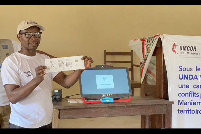 Jean Tshomba demonstrates the procedure for voting during an educational program at Victor Wetchi United Methodist Church in the Kibombo District in Congo. Tshomba is coordinator of the local disaster management office. Financial support from the United Methodist Committee on Relief helped fund a program to prevent election-related violence. Photo by Chadrack Tambwe Londe, UM News.