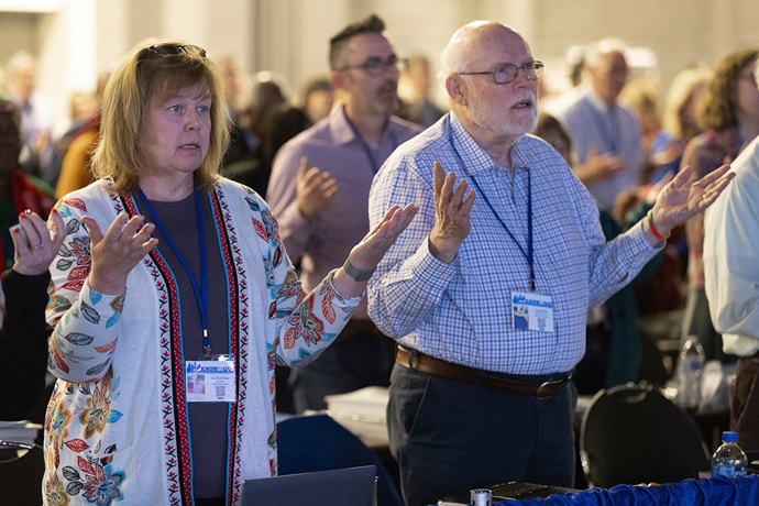 The Rev. Amy Shanholtzer of the West Virginia Conference and Tracy Merck of the Western Pennsylvania Conference pray during opening worship at the 2024 United Methodist General Conference in Charlotte, N.C. Photo by Mike DuBose, UM News.