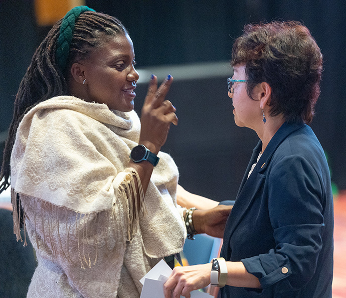 Juliet Nabukalu (à esquerda) da Conferência Uganda-Sudão do Sul fala com Sung-ok Lee das Mulheres Unidas na Fé durante um briefing para delegados de fora dos Estados Unidos realizado antes da Conferência Geral Metodista Unida em Charlotte, N.C. Foto de Mike DuBose, Notícias MU.