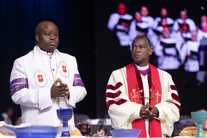 Bishop Mande Muyombo (left) of the North Katanga Episcopal Area and Gaspar João Domingos of the Angola West Episcopal Area bless the elements of Holy Communion during April 23 opening worship at the United Methodist General Conference in Charlotte, N.C. Photo by Mike DuBose, UM News.