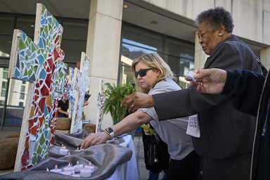 Participants place flameless candles in front of crosses during a Service of Lament, Confession and Hope on April 29 at the United Methodist General Conference in Charlotte, N.C. The service commemorated victims of sexual abuse within the denomination and called the church to greater accountability. Photo by Paul Jeffrey, UM News.