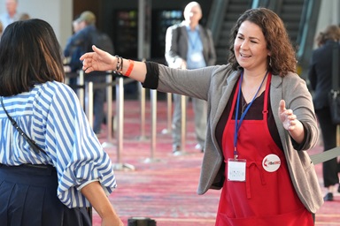 Volunteer Nicole Jones helps welcome an attendee to the United Methodist General Conference in Charlotte, N.C., on April 29. More than 1,000 volunteers have donned the distinctive red apron as volunteers at the legislative assembly, which continues through May 3 at the Charlotte Convention Center. Photo by Larry McCormack, UM News.