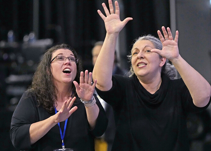As intérpretes de língua gestual Andrea Raye (à esquerda) e Tina McDaniel cantam e dançam ao som de “Stand by Me” durante um intervalo a 3 de maio na Conferência Geral Metodista Unida em Charlotte, C.N. Foto de Larry McCormack, Notícias MU.
