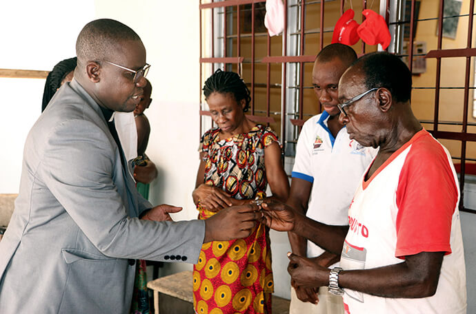 The Rev. Isaac Broune (left), pastor of Bethel United Methodist Church in the Elephant neighborhood of South Abidjan, Côte d’Ivoire, shares communion with the Ohouo family (from left, Appolos, Fabrice, Chiadon and Chantal) during a service in their home in 2020. While churches were closed because of the COVID-19 pandemic, members conducted services at home with resources provided by their pastors. File photo by John Mel, UM News.