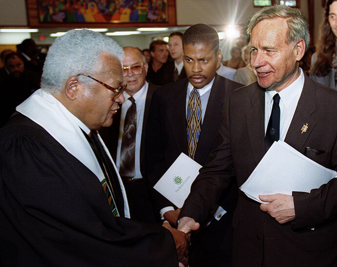Le Révérend James M. Lawson Jr (à gauche), pasteur méthodiste, s'entretient avec l'avocat William Pepper à l'issue des funérailles de James Earl Ray, l'assassin condamné du Révérend Martin Luther King Jr, à Nashville (Tennessee) en 1998. À l'arrière-plan, le frère de Ray, Jerry Ray (à gauche), et le neveu de King, Isaac Farris Jr. Photo de Mike DuBose, UM News.