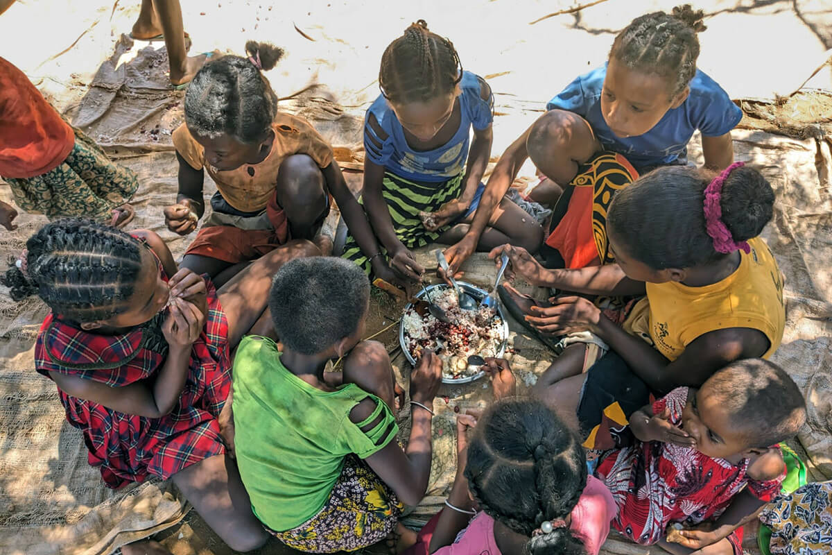 Des enfants partagent la nourriture distribuée par l'Église Méthodiste Unie à Andranokaky, dans le Sud de Madagascar. Les membres de l'Église Méthodiste Unie d'Ambodifasika, sur l'île, ont distribué les vivres aux personnes touchées par le changement climatique. Photo par Justin Rakotoarimanana.