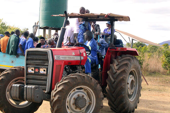 A tractor pulls residents at Nyadire Mission in Mutoko, Zimbabwe, to collect food aid provided by members of The United Methodist Church. Families received a monthly gift of 44 pounds of mealie meal (cornmeal), a gallon of cooking oil and nine pounds each of sugar, flour and rice. Photo by Kudzai Chingwe, UM News.