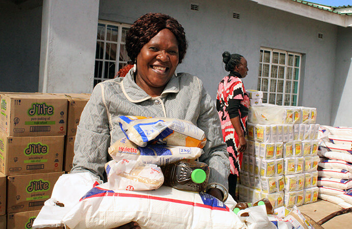 Mupunga Wonai, a Nyadire Teachers College lecturer, carries food supplied by The Nyadire Connection, a longtime partner of The United Methodist Church’s Nyadire Mission in Mutoko, Zimbabwe. She said the food relief will make life easier as residents deal with the effects of El Nino-induced drought. Photo by Kudzai Chingwe, UM News.
