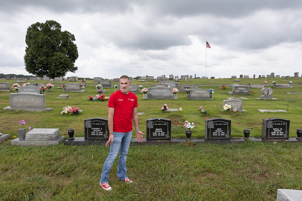 The Rev. Tim Holton, a United Methodist pastor, visits family graves at the Simpson Cemetery in Eagleville, Tenn. In 1997, his cousin, Daryl Holton, killed his four children with a military-style rifle and was eventually executed in Tennessee’s electric chair. He is buried beneath the light-colored headstone at left, next to the graves of his children. Tim Holton now serves on the board of Tennesseans for Alternatives to the Death Penalty and ministers to death row inmates as a volunteer chaplain at Riverbend Maximum Security Institution in Nashville, Tenn. Photo by Mike DuBose, UM News.