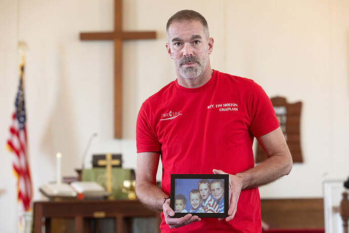 The Rev. Tim Holton holds a photo of cousin Daryl Holton’s four children whom Daryl Holton killed in 1997. From left in the framed photograph are Kayla, Eric, Brent and Stephen. Photo by Mike DuBose, UM News.