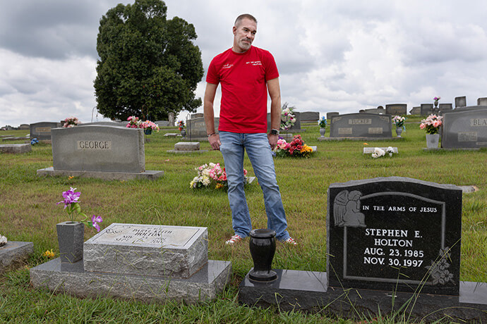 The Rev. Tim Holton visits the graves of his cousin, Daryl Holton (left), and Daryl Holton’s son, Stephen, at the Simpson Cemetery in Eagleville, Tenn. Photo by Mike DuBose, UM News.