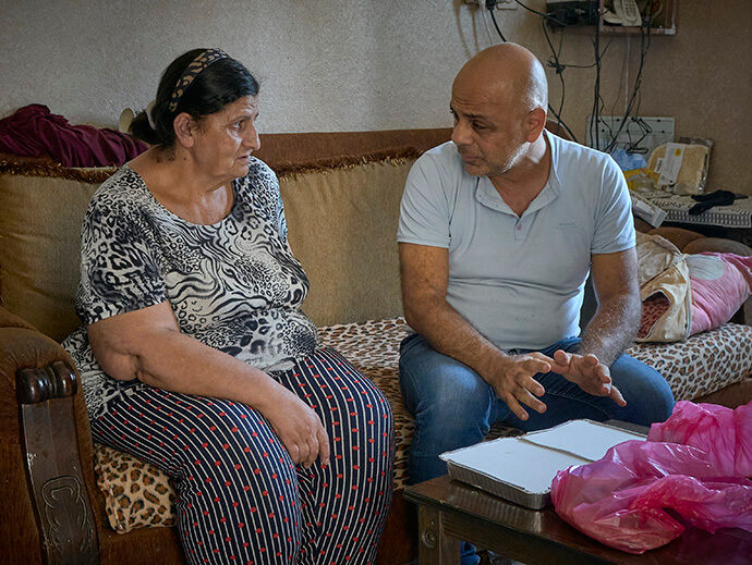 Ramzi Qubrosi (right) talks with Raida Qassis as he delivers food to her in her home in Beit Sahour, a town in the Israeli-occupied West Bank near Bethlehem. The food delivery provides nutrition and human contact to people adversely affected by the decline in tourism that has ravaged Bethlehem's economy since the October 2023 Hamas attack on Israel and the subsequent Israeli war in Gaza. Photo by Paul Jeffrey, UM News.