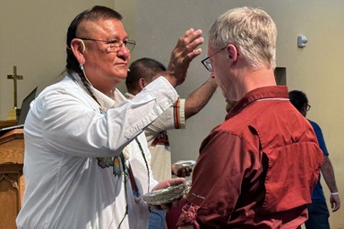 The Rev. Calvin Hill, a Navajo holy man and pastor at First United Methodist Church in Newcastle, Wyo., puts cedar ashes on Doug Tzan, assistant dean at Wesley Theological Seminary, in a calling your name ceremony Sept. 11 during the 10th Historical Convocation at Bozeman United Methodist Church in Bozeman, Mont. The convocation featured a detailed report on The United Methodist Church’s involvement with U.S. boarding schools for Native American children. Photo by the Rev. Jeremy Smith. The Rev. Calvin Hill, a Navajo holy man and pastor at First United Methodist Church in Newcastle, Wyo., puts cedar ashes on Doug Tzan, assistant dean at Wesley Theological Seminary, in a calling your name ceremony Sept. 11 during the 10th Historical Convocation at Bozeman United Methodist Church in Bozeman, Mont. The convocation featured a detailed report on The United Methodist Church’s involvement with U.S. boarding schools for Native American children. Photo by the Rev. Jeremy Smith.