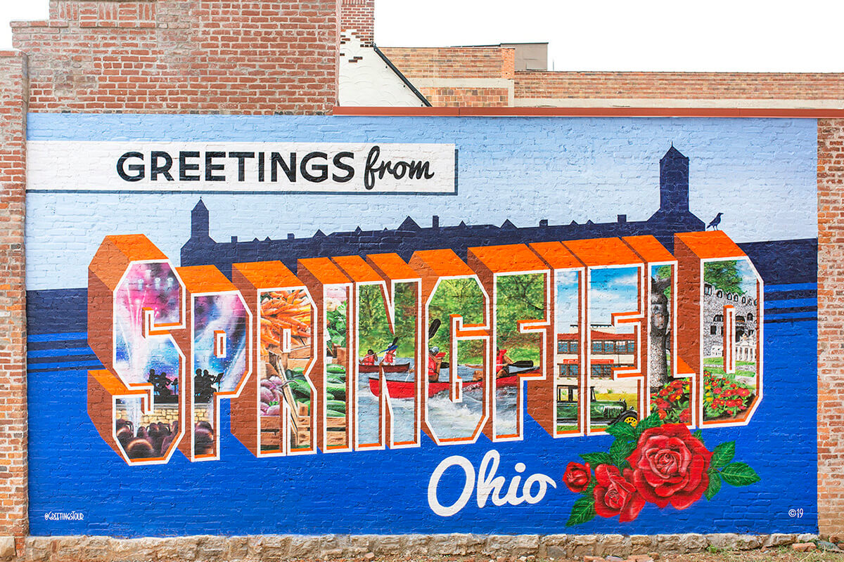 O mural Greetings from Springfield (Saudações de Springfield), Ohio, se tornou um marco do centro da cidade. Os Metodistas Unidos em Ohio e além estão se mobilizando para estender uma recepção semelhante e mostrar apoio aos imigrantes haitianos na cidade. Springfield sofreu mais de 30 ameaças de bomba após ser alvo de retórica anti-imigrante baseada em falsas alegações. Foto cortesia da Greetings Tour; usada com permissão.