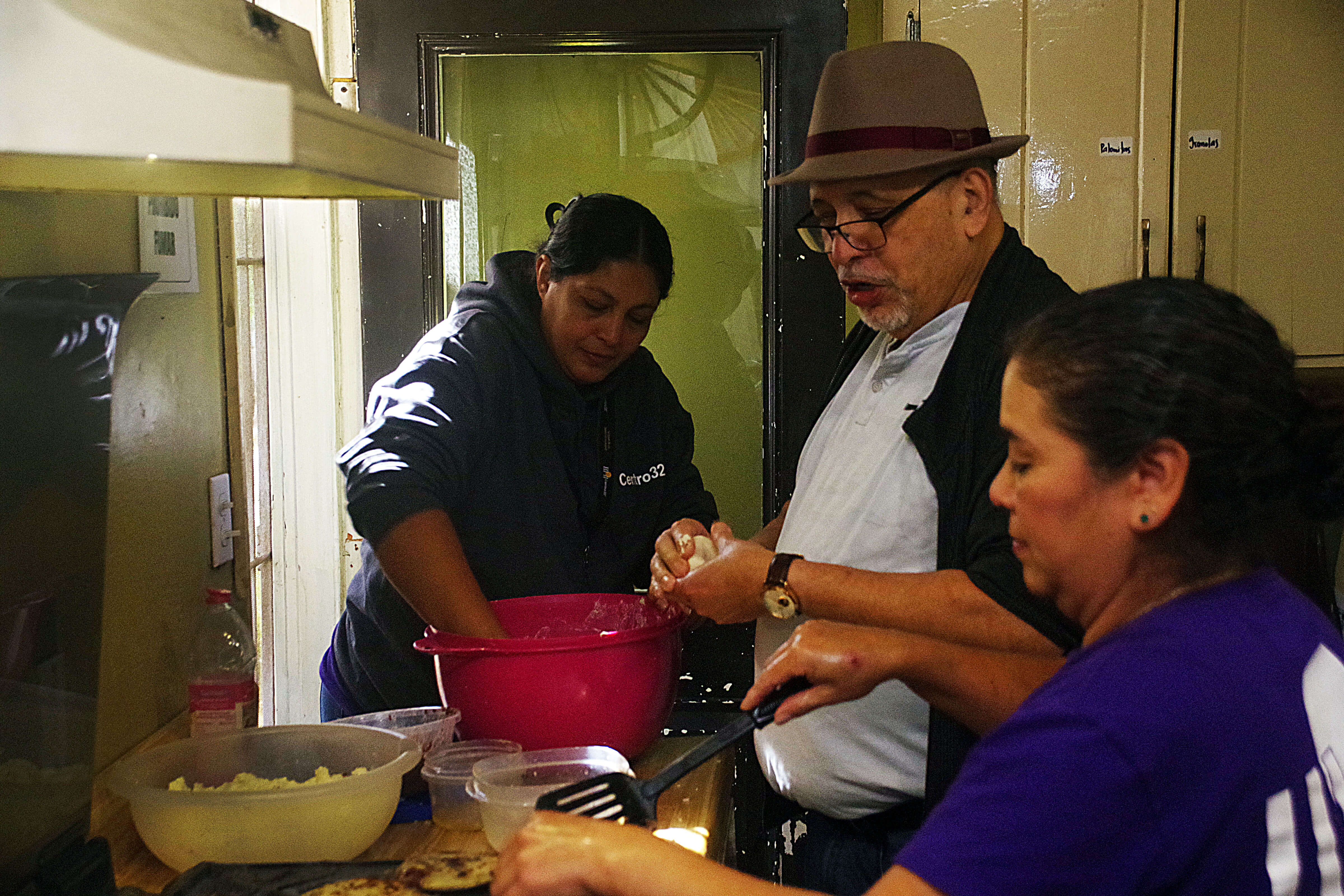 El Rev. Jorge Rodríguez, miembro de MARCHA de la Jurisdicción Oeste colabora con el equipo de voluntarias del Centro 32, en la elaboración de las pupusas que fueron servidas en el almuerzo que diariamente se sirve a las familias migrantes. 