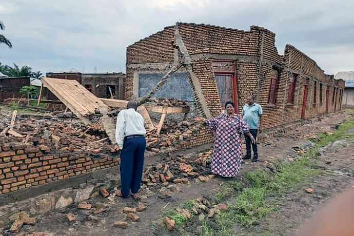 La Révérende Valentine Cimpaye, surintendante du district de Bujumbura, se tient devant l'un des bâtiments détruits du Lycée Technique Mgr Jean Alfred Ndoricimpa à Bujumbura, au Burundi. L'École Méthodiste Unie a été gravement endommagée par les récentes tempêtes. Niyomwungere Juvénal (à gauche), directeur technique du lycée, et Makarakiza Obed (à droite), responsable laïc du district, sont également présents. Photo par Jerome Ndayisenga, UM News.