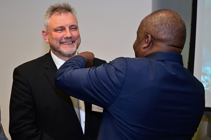 El Obispo Mande Muyombo coloca el prendedor de obispo en la solapa del Rev. Werner Philipp después de que fue elegido obispo metodista unido en la Conferencia Central de Alemania el 13 de febrero en Würzburg, Alemania. Foto de Klaus Ulrich Ruof, Relaciones Públicas de EmK.