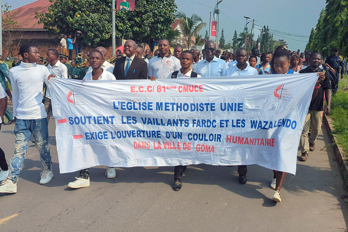 Des jeunes tiennent une banderole lors d'un rassemblement pour la paix à Kindu, au Congo, au début du mois de février. Derrière eux, des membres du clergé Méthodiste Uni et d'autres jeunes marchent pour réclamer la paix dans l'est du Congo, où les combats entre les rebelles du M23 et l'armée congolaise se sont intensifiés ces derniers mois. Photo par Chadrack Tambwe Londe, UM News.