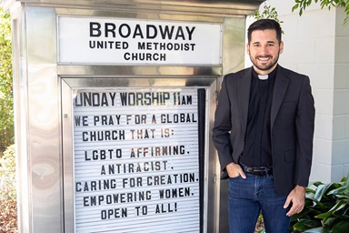 O Rev. Rushing Kimball está ao lado de uma placa da Igreja Metodista Unida da Broadway em Orlando, Flórida. A congregação e Kimball pessoalmente têm sofrido protestos e ameaças de pessoas que se opõem à postura de afirmação LGBTQ da igreja. Foto cortesia de Kimball, Igreja Metodista Unida da Broadway. O Rev. Rushing Kimball está ao lado de uma placa da Igreja Metodista Unida da Broadway em Orlando, Flórida. A congregação e Kimball pessoalmente têm sofrido protestos e ameaças de pessoas que se opõem à postura de afirmação LGBTQ da igreja. Foto cortesia de Kimball, Igreja Metodista Unida da Broadway.