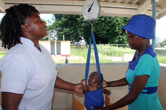 Evidence Matemachani (left) weighs Takudzwa Chihwai during his six-week check-up as his mother, Emily Chindenga, watches at Chindenga clinic in Mutoko, Zimbabwe. The center is the sixth rural health clinic under the United Methodist Nyadire Mission Hospital to be revitalized over the past decade with support from The Nyadire Connection and the United Methodist Board of Global Ministries. Photo by Kudzai Chingwe, UM News.