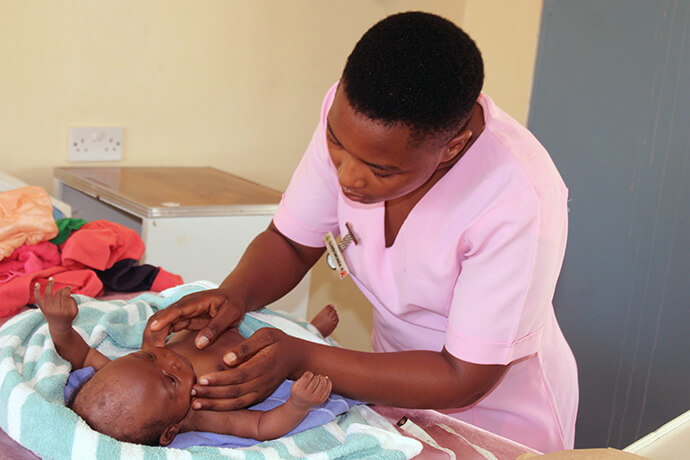 Kudzai Gumbomunda assesses 6-week-old Takudzwa Chihwai at Chindenga clinic in Mutoko, Zimbabwe. The renovated health center now has electricity, water, an outpatient department, a mother’s waiting shelter and spacious rooms. Photo by Kudzai Chingwe, UM News.
