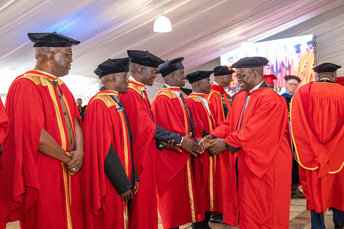 Le secrétaire permanent à l'enseignement supérieur et tertiaire du Zimbabwe et ancien vice-chancelier de Africa University, Fanuel Tagwira (à droite), félicite les premiers diplômés du premier doctorat en aumônerie militaire, un programme de partenariat avec le Wesley Theological Seminary de Washington, qui est lié à l'Église Méthodiste Unie. Les dix aumôniers masculins, issus de l'armée, de l'armée de l'air, de la police et des services correctionnels de quatre pays d'Afrique australe ( ), ont obtenu leur diplôme en mai. Photo reproduite avec l'aimable autorisation du Bureau des affaires publiques de Africa University.