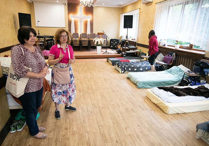 The Revs. Alla Vuksta (left) and Yulia Starodubets check on people displaced by the war in Ukraine who were staying in the sanctuary at Kamyanitsa United Methodist Church in western Ukraine in May of 2022. Today, Starodubets is living with refugees at Under the Castle, a United Methodist mission center near Kam’yanytsya, Ukraine. File photo by Mike DuBose, UM News.