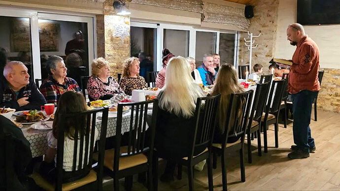 Displaced Ukrainians staying at Under the Castle near Kam’yanytsya, Ukraine, eat a meal together during Christmas of 2024. About 40 people are staying at the United Methodist mission center, which was purchased through a grant from the United Methodist Committee on Relief. Photo by the Rev. Yulia Starodubets, courtesy of Global Ministries.