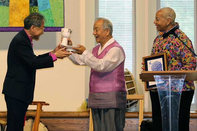 Bishop Chung-Suk Kim (left), president of the Council of Bishops of the Korean Methodist Church, and United Methodist Bishops Hee-Soo Jung (center) and Tracy S. Malone exchange commemorative gifts during the opening dinner for a gathering celebrating 140 years of Methodist mission in Korea and Ohio. Photo by the Rev. Thomas E. Kim, UM News.