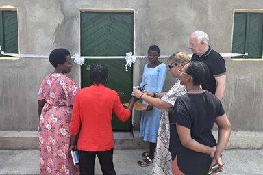 The Rev. Sunny Brown Farley, coordinator of the United Methodist Global AIDS Committee, helps cut the ribbon on a new house built for a mother living with HIV in Rwanda. Joining in the festivities are neighboring women and the Rev.  Donald E. Messer, a member of the United Methodist Global AIDS Committee. Photo courtesy of Donald E. Messer.  The Rev. Sunny Brown Farley, coordinator of the United Methodist Global AIDS Committee, helps cut the ribbon on a new house built for a mother living with HIV in Rwanda. Joining in the festivities are neighboring women and the Rev.  Donald E. Messer, a member of the United Methodist Global AIDS Committee. Photo courtesy of Donald E. Messer.