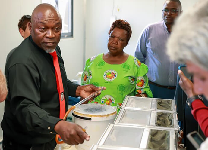 Petros Kawadza, assistant senior en insecticulture pour le programme ZENTO de l'université Africa, montre aux visiteurs comment le laboratoire élève des moustiques à des fins de test. Grâce au soutien financier du Conseil méthodiste unifié des ministères mondiaux, l'université a rouvert son laboratoire de recherche. Lancé en 2021 avec le soutien de l'USAID, le programme est devenu le principal centre de surveillance du paludisme au Zimbabwe. Photo de Ben Smith, UM News.