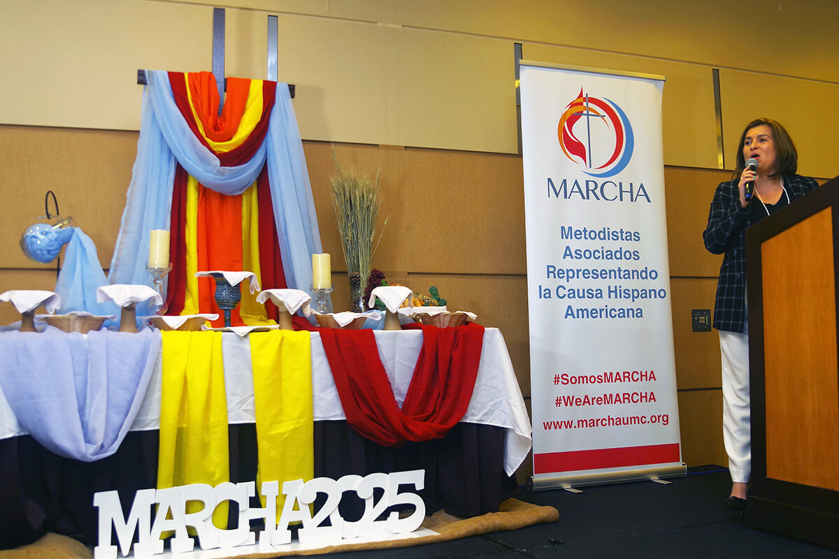 Emma Escobar, president of MARCHA (Associated Methodists for the Hispanic-Latino American Cause), speaks during the opening ceremony of the caucus’ 53rd annual assembly Aug. 1 in Chicago. The altar, prepared by the Spanish-Latino Ministries of the Northern Illinois Conference, offered a display of sacramental elements and colors as a liturgical expression of the diversity of races, cultures, theological interpretations, ages and genders that make up MARCHA. Photo by the Rev. Gustavo Vasquez, UM News.