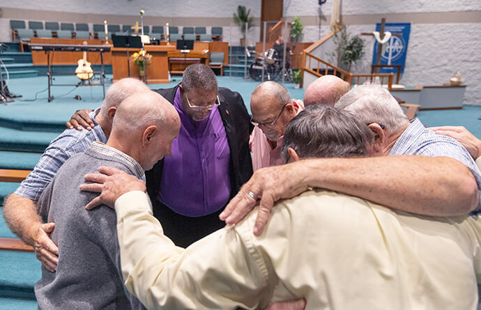 L'Evêque Frank Beard (au centre) prie avec des hommes de l'Eglise Méthodiste Elkhart Faith avant le culte. Photo de Mike DuBose, UM News.