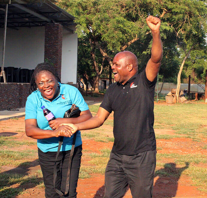 Mabasa Muzhizhizhi, associate pastor of Chisipiti United Methodist Church, raises his fist in triumph after ziplining during a Women of Substance retreat at Lake Chivero in Harare, Zimbabwe, as a group member congratulates him. Women of Substance includes Chisipiti United Methodist Church members who have never married, are widowed or divorced. Photo by Kudzai Chingwe, UM News.  