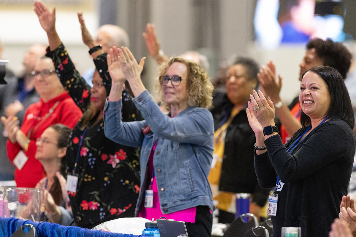 West Ohio delegates raise their arms in praise during morning worship at the 2024 United Methodist General Conference in Charlotte, N.C. From right are the Revs. April Casperson and Dee Stickley-Miner and Tracy Chambers. On Nov. 5, the Council of Bishops announced annual conference voters ratified four ballots of constitutional amendments passed at General Conference. In addition to regionalization, the ratified amendments deal with inclusion in church membership, racial justice and educational requirements for clergy. Casperson helped lead the task force that championed the passage of the amendment on inclusiveness. File photo by Mike DuBose, UM News.