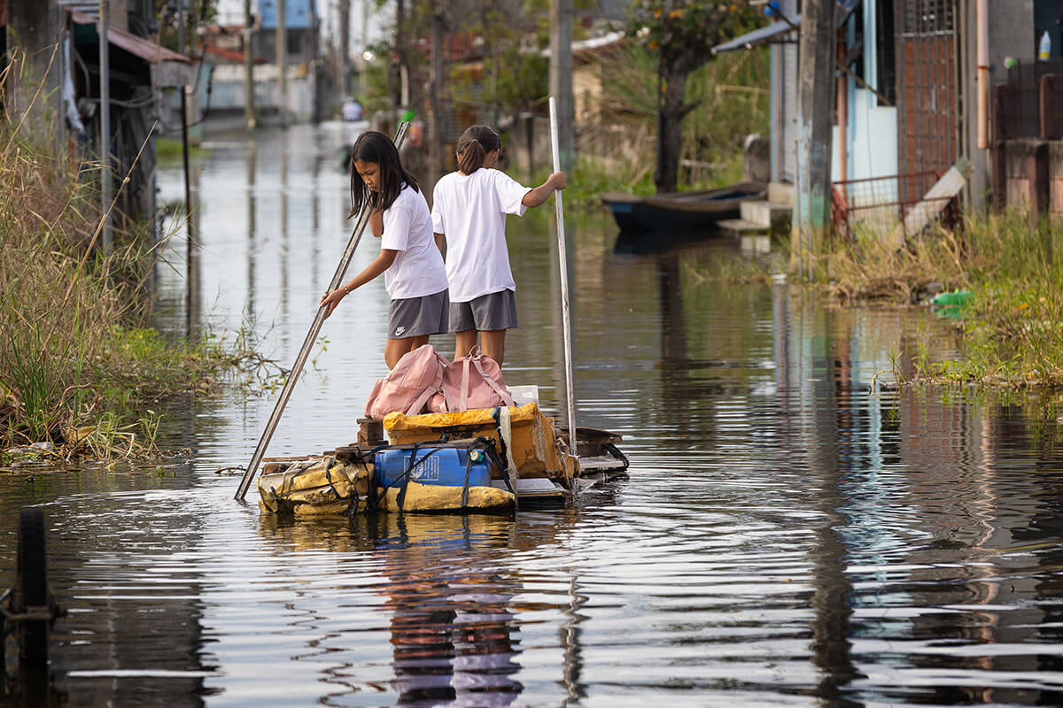 Schoolgirls journey home on a homemade raft they guide down a flooded street in Calumpit, Philippines, after Typhoon Carina in July 2024. As climate change continues to impact livelihoods, economies and habitats around the world, the Council of Bishops is reiterating its commitment to creation care. File photo by Mike DuBose, UM News. 
