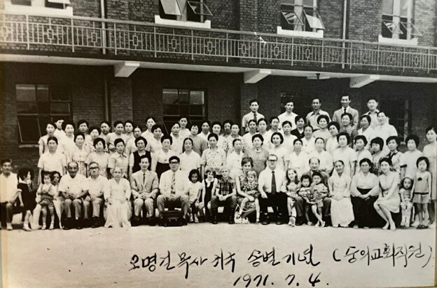 1971년 7월 4일, 조오지 오글(George E. Ogle) 목사가 박사학위를 마치기 위해 미국으로 떠나기 전, 소속 교회였던 인천 숭의감리교회에서 열린 송별회를 마치고 찍은 기념사진. 사진 속에는 조오지 오글(George E. Ogle) 목사와 도로시 오글(Dorothy L. Ogle) 선교사 부부가 함께 서 있으며, 오글 목사 옆에는 당시 감독이자 훗날 기독교대한감리회 감독으로 선출된 이호문 목사가 나란히 자리하고 있다. 사진 제공, 인천 숭의감리교회.