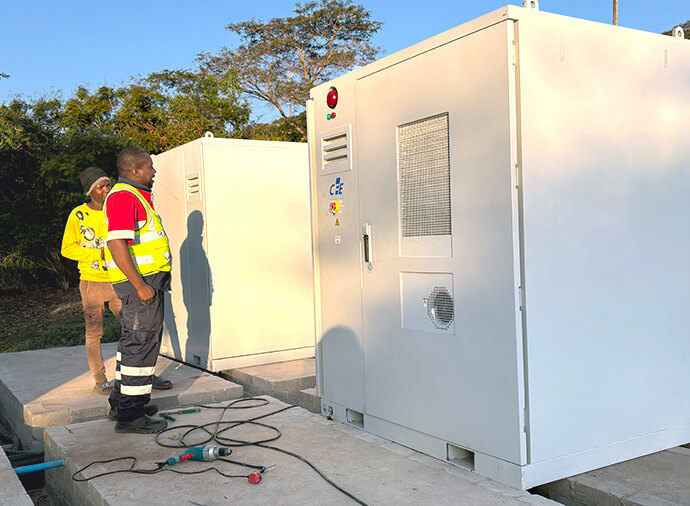 Des techniciens de l'université Africa à Mutare, au Zimbabwe, observent les nouvelles unités de stockage solaire pour batteries et onduleurs installées dans l'établissement en juin. La lumière et la chaleur absorbées par des centaines de panneaux rectangulaires sont converties en énergie pour cette école liée à l'Église Méthodiste Unie. Photo d'Eveline Chikwanah, UM News.