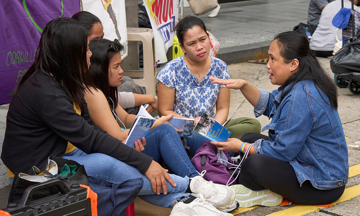 Amy Toreno (right) teaches other migrant workers about their rights using a book, "Know Your Rights & Responsibilities," published by the Mission for Migrant Workers, to guide the discussion. A migrant worker herself, Toreno is a volunteer with the group, which receives support from United Women in Faith and the United Methodist General Board of Global Ministries. Photo by Paul Jeffrey, UM News.
