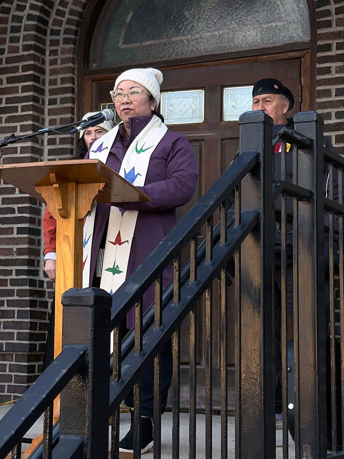 The Rev. Jennifer Ikoma-Motzko, pastor of spiritual care and formation at Park Avenue United Methodist Church in Minneapolis, leads a prayer vigil outside the church on Jan. 9. Ikoma-Motzko, a fourth-generation Japanese American whose stole depicts origami doves, spoke at both the vigil and Sunday worship about her maternal grandmother’s experience with Japanese internment during World War II. “It astounds me and it grieves me … to see that same sort of fear and violence happening here in our communities.” Photo courtesy of Park Avenue United Methodist Church. 