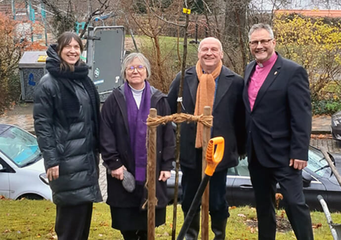 (From left) Pastor Rebekka Tibbe of the Evangelical Lutheran Church of St. Jürgen, the Rev. Gillian Horton-Krüger of Flensburg United Methodist Church and her husband, Peter Krüger, and United Methodist Bishop Werner Philipp pose for a photo after planting an apple tree at the St. Jürgen church, where the Flensburg congregation meets. Photo by Isabel Philipp.