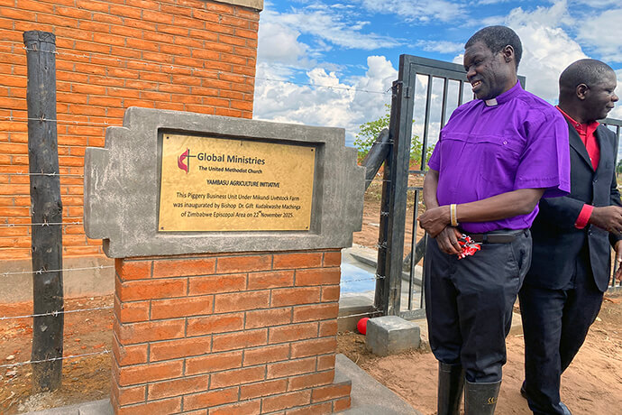 L'évêque Gift K. Machinga admire un panneau à la ferme laitière Mikundi à Mikundi, au Malawi, après une cérémonie d'inauguration de la ferme en novembre. La ferme est soutenue par l'initiative agricole Yambasu du Conseil méthodiste unifié des ministères mondiaux. Au cours de sa visite, Machinga a conduit les membres de l'Église locale dans un moment de prière et a souligné que des projets comme celui de Mikundi sont la clé de l'avenir de l'Église. Photo de Francis Nkhoma, UM News.