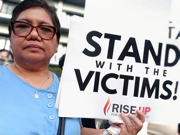 United Methodist Deaconess Rubylin G. Litao holds a sign that reads, “Stand with Victims,” March 11 in Quezon City, Philippines, at a protest marking the one-year arrest of former Philippine President Rodrigo Duterte. Photo courtesy of Rubylin Litao.