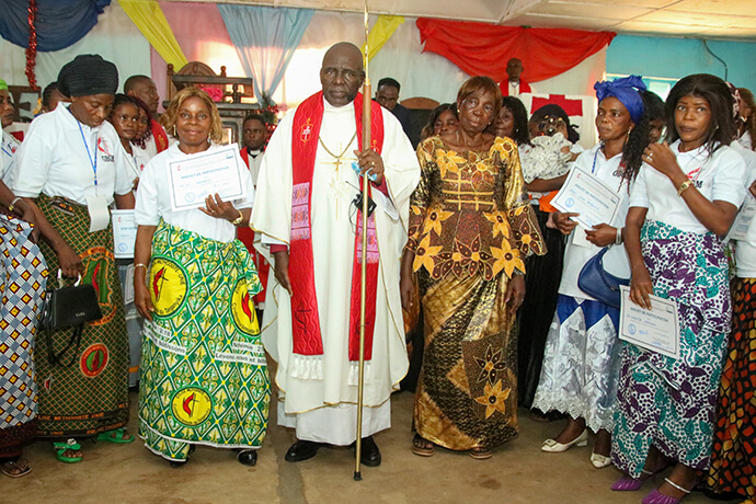 Aziza Mahamudi, épouse d’un pasteur, pose fièrement avec son certificat aux côtés de l’Évêque Méthodiste Uni Antoine Kalema Tambwe et de son épouse, Charlotte Ngole Kitete, entourée d’autres diplômées à Kindu. Après avoir accompagné son mari dans son ministère pendant plus de 30 ans, Maman Aziza a participé à cette formation afin de renforcer ses compétences en leadership et de mieux soutenir le développement social et spirituel des communautés rurales du Congo oriental. Photo de Chadrack Tambwe Londe, UM News.