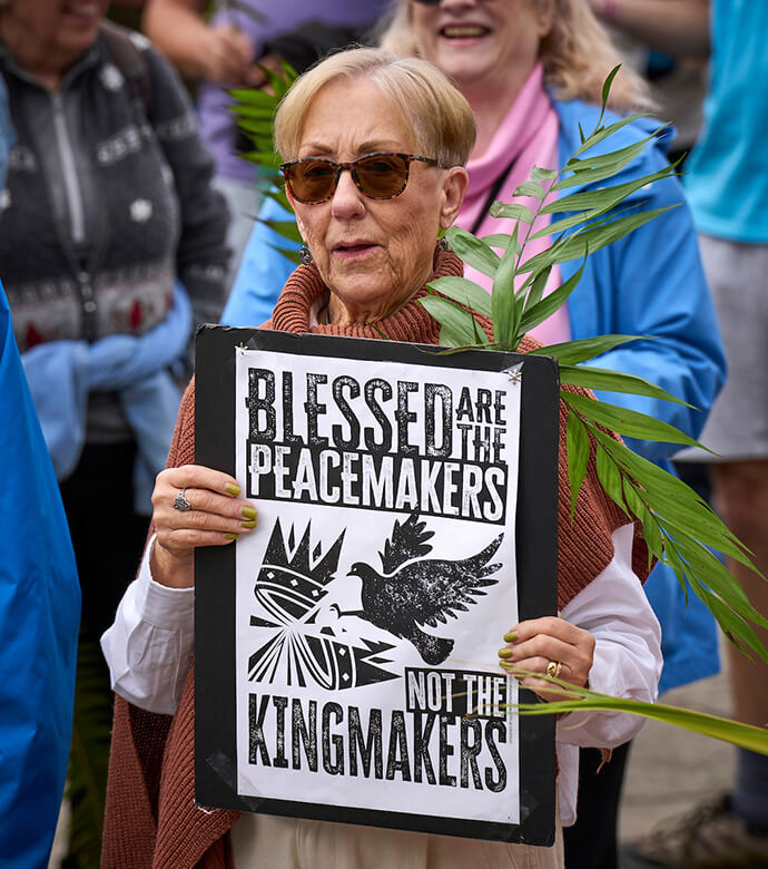 Une femme défile avec une pancarte et une feuille de palmier lors d'une manifestation organisée le dimanche des Rameaux, le 29 mars, à Eugene, dans l'Oregon. Photo de Paul Jeffrey, UM News.