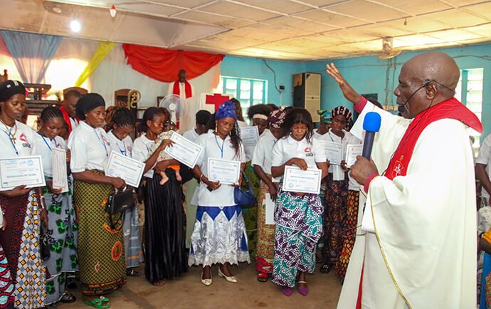 Bishop Antoine Kalema Tambwe of the East Congo Episcopal Area raises his hand in blessing as he prays for pastors’ wives following a certificate presentation ceremony in Kindu, Congo. The women received training from The United Methodist Church to help them become leaders and key agents of community development within their rural parishes. Photo by Chadrack Tambwe Londe, UM News.